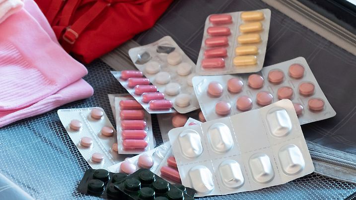 Travel concept. opened packed suitcase on bed in hotel room, pills and medicine