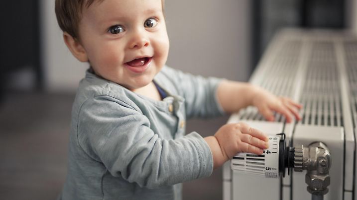 Portrait of smiling baby boy playing with thermostat of heater model released Symbolfoto property released PUBLICATIONxINxGERxSUIxAUTxHUNxONLY SEBF00022