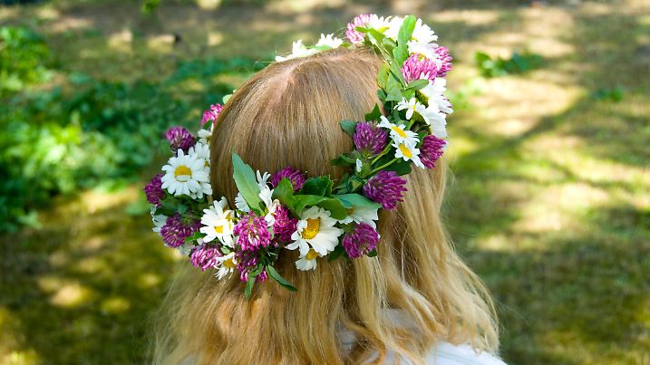Ein Mädchen trägt einen Blumenkranz zu Midsommar auf dem Kopf.