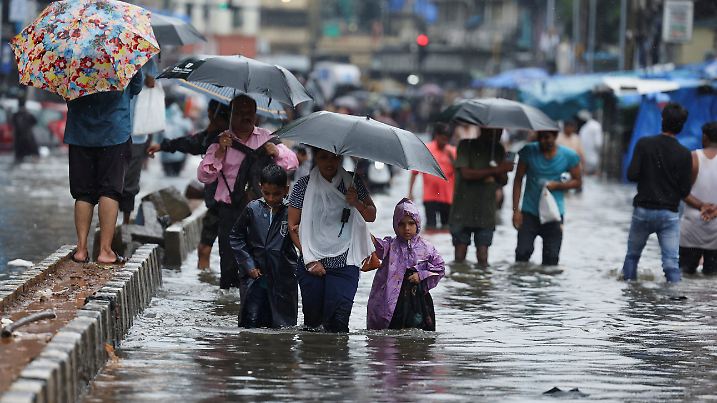 People wade through a waterlogged street following heavy rainfall in Mumbai