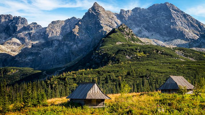 Verlassene Hirtenhäuser vor der zackigen Silhouette der Hohen Tatra.
