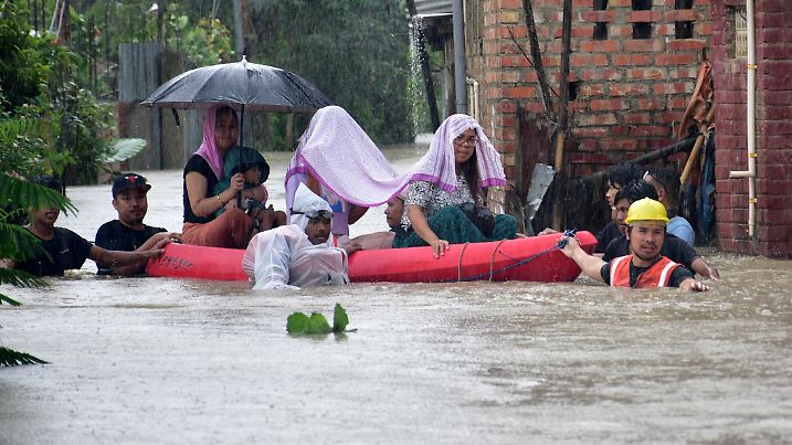 Flood-affected people are moved to safer places through a water-logged road during rains in Imphal East