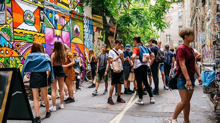 Touristen und Einheimische besuchen das Anne Frank Zentrum. Das Café ist ein beliebter Treffpunkt in Berlin und das Äußere ist eine bunte Gasse, die mit Graffiti bedeckt ist.