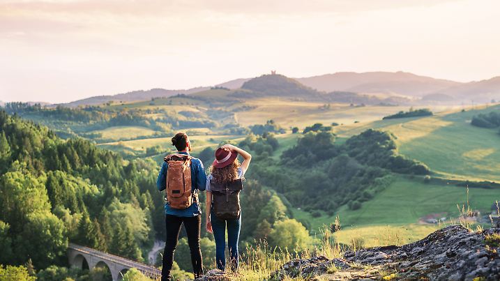 Rückansicht eines jungen Touristenpaares, das in der Natur wandert und sich ausruht.
