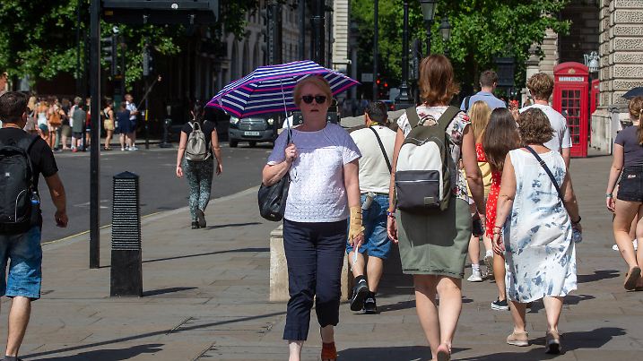 July 18, 2022, London, England, United Kingdom: A person carrying an umbrella as a protection against sun rays is seen