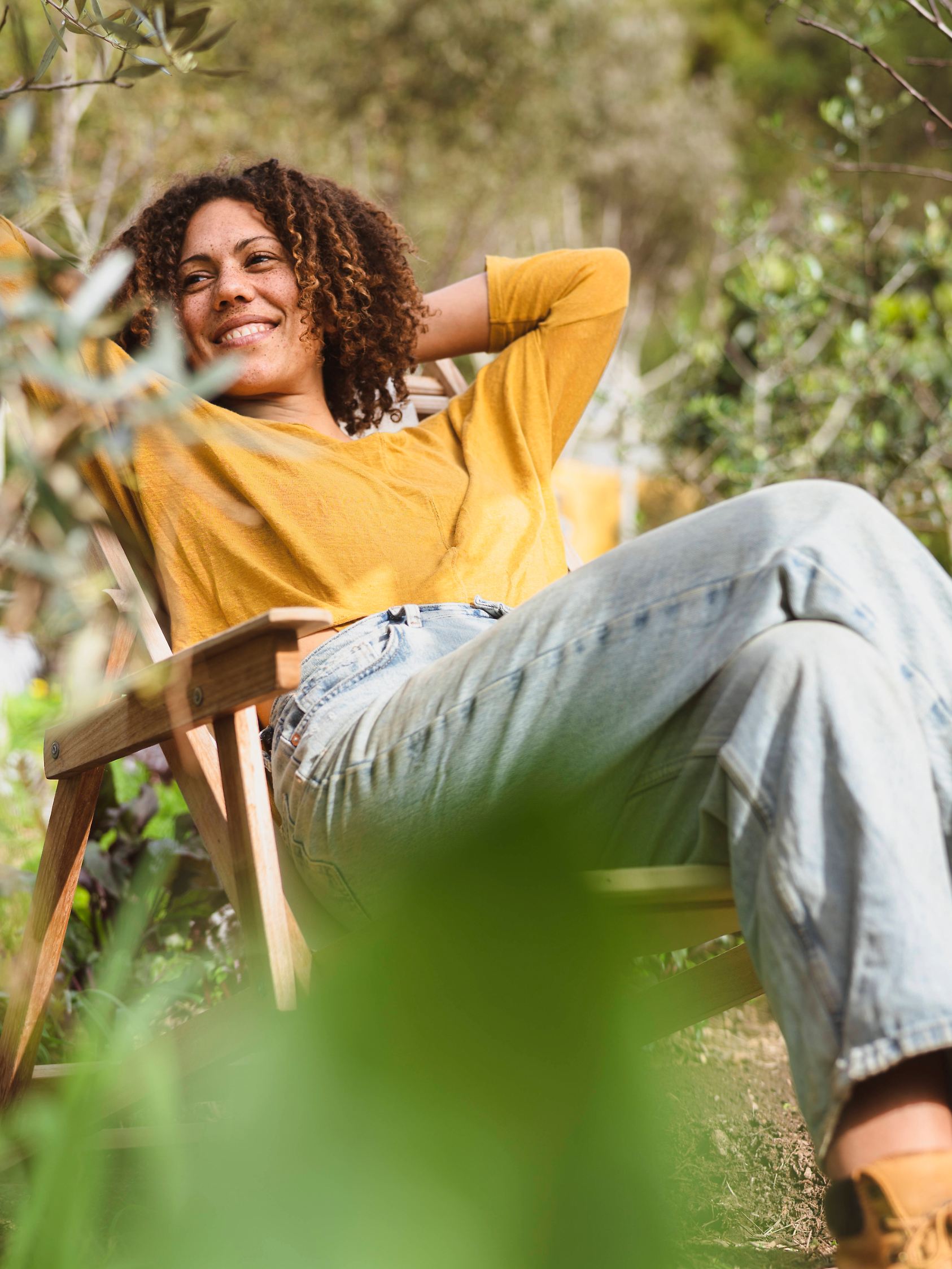 Eine Frau sitzt in einem Gartenstuhl und genießt die Sonne. 