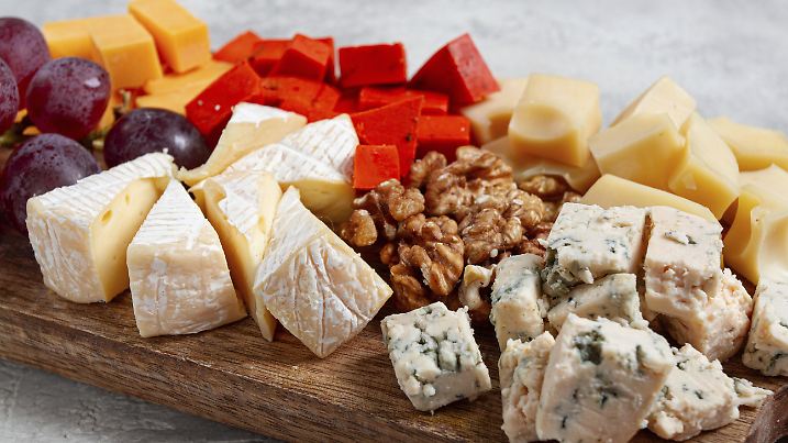 Gemischter Käse auf einem Holzbrett, mit Trauben und Walnüssen, Vorspeise...