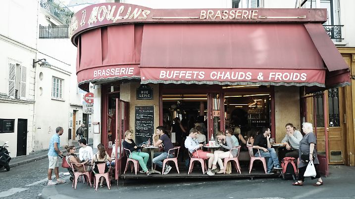 Paris, France - September 09, 2014: People enjoy a warm night outside Cafe des 2 Moulins in Montmartre district in Paris, France. Cafe des 2 Moulins is a famous landmark in Paris after the famous French film Amelie directed by Jean-Pierre Jeunet.