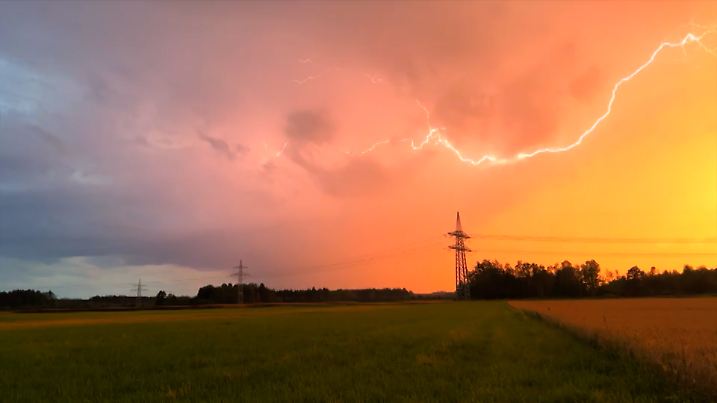 Gewitter lassen es hinter einem Strommast aufblitzen.
