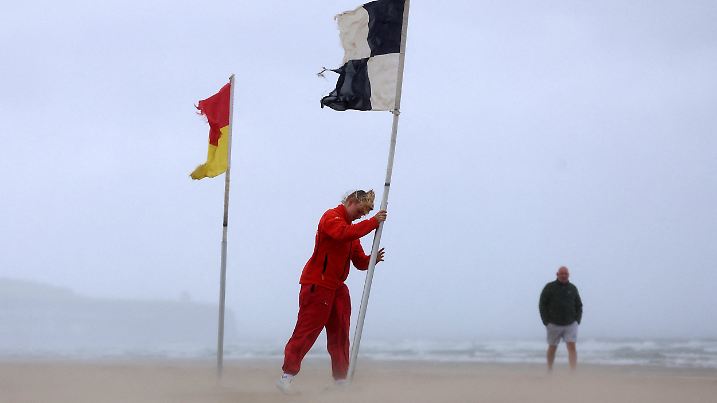 Eine Rettungsschwimmerin stellt eine Flagge an der Küste Nordirlands auf