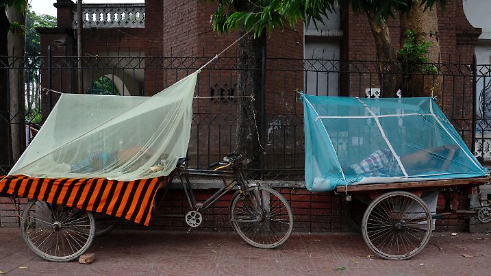 FILE PHOTO: People sleep on three-wheeler carts using mosquito nets, following a surge of dengue-infected patients in Dhaka