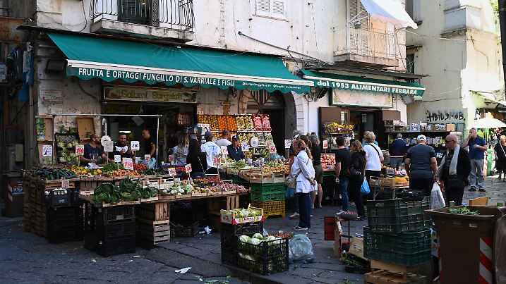Naples, Italy, september 14, 2024 : Customers in front of a fruit and vegetable stall in front of a shop in the Pignasecca market in the city of Naples