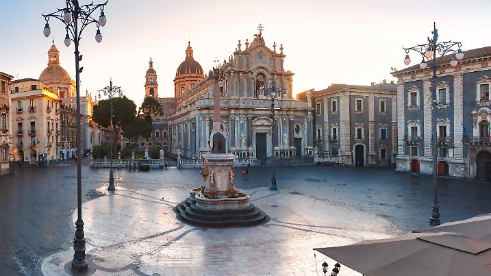 The first sunray on Piazza Duomo in Catania and the Cathedral of Santa Agatha and Liotru, symbol of Catania at sunrise, Sicily,