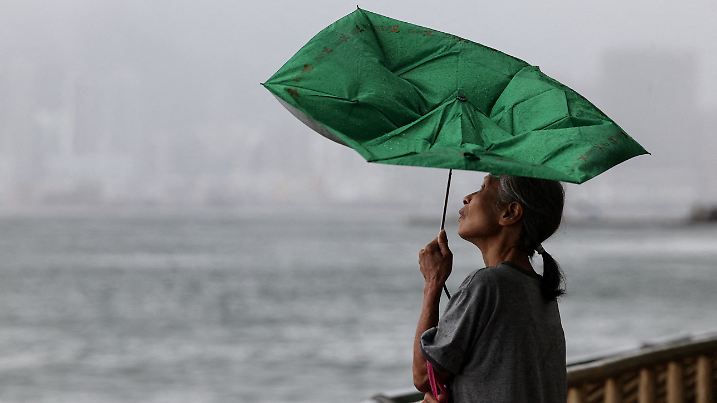 A woman holds an umbrella inverted by winds as Tropical Storm Tapah approaches in Hong Kong