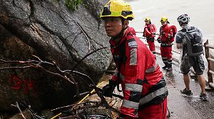 A firefighter moves a fallen branch after Super Typhoon Ragasa passes, as he assesses damage from storm surge and flooding, in Hong Kong