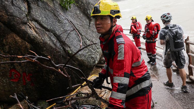 A firefighter moves a fallen branch after Super Typhoon Ragasa passes, as he assesses damage from storm surge and flooding, in Hong Kong