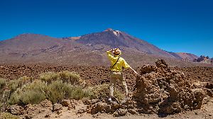 Eine Touristin im gelben Hemd und mit Strohhut bewundert die atemberaubende Aussicht auf den Teide auf Teneriffa