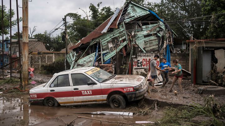 11.10.2025, Mexiko, Poza Rica: Nachbarn versammeln sich um ein beschädigtes Haus nach heftigen Regenfällen in Poza Rica im Bundesstaat Veracruz. 