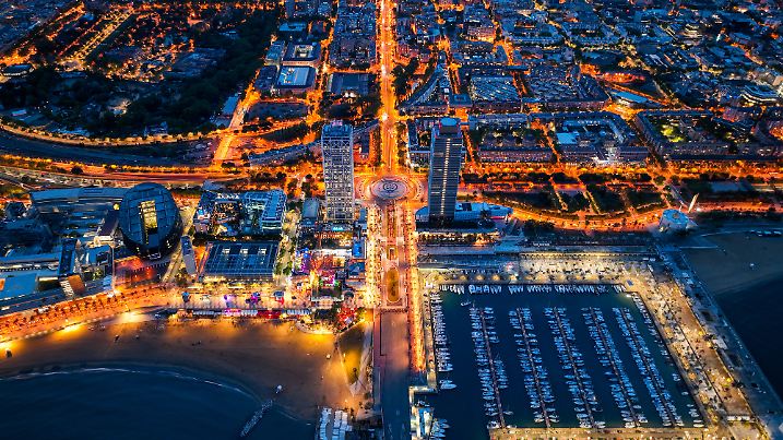 Overhead night view of Port Olimpic marina and city lights along the beach