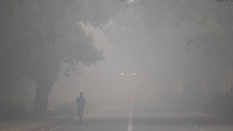 A man jogs on a road shrouded in smog on the day after Diwali, in New Delhi