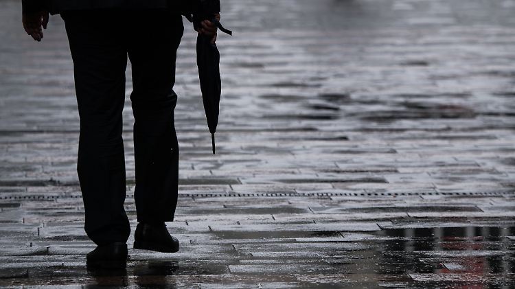 Ein Passant geht mit Regenschirm in der Hand durch Mainz