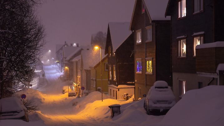 a road and houses covered by snow at polar night during snow storm, Tromsø, Norway, March 2025
