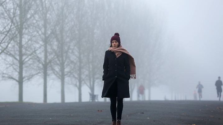 November 27, 2020, London, United Kingdom: A woman wrapped up warm walk on the street on a foggy and cold morning in Lon