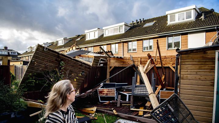 21.10.2021, Niederlande, Barendrecht: Eine Frau steht einen Tag nach dem Sturm vor einem beschädigten Haus im Wohngebiet Ter Leede. Starke Sturmböen haben in den Niederlanden Schäden verursacht. Mehrere Menschen wurden etwa durch herabfallende Dachziegel und entwurzelte Bäume leicht verletzt, wie die Behörden am Donnerstag (21.10.2021) mitteilten. Foto: Robin Utrecht/ANP/dpa +++ dpa-Bildfunk +++