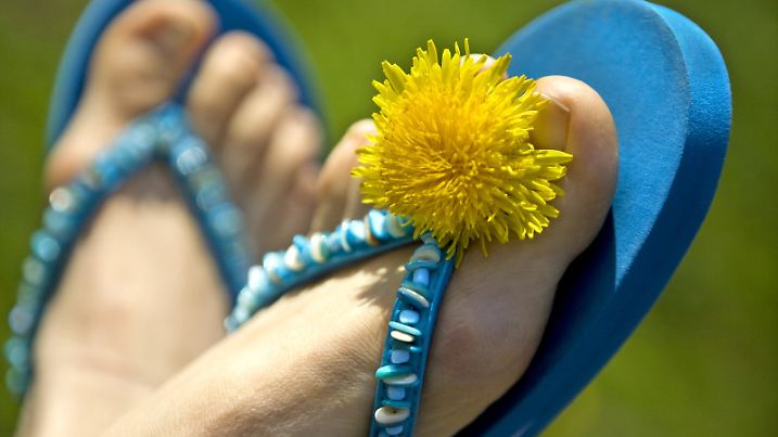ARCHIV - ILLUSTRATION - Ein Frau trägt am 13.04.2009 in Berlin ein Paar Flip-Flops, verziert mit Löwenzahn. Flip-Flop-Wetter zu Ostern: Bei hochsommerlichen Temperaturen bis zu 25 Grad haben die Menschen in Deutschland den Ostersonntag hauptsächlich im Freien genossen. Foto: Arno Burgi dpa (zu dpa "Sommer-ABC 2010" vom 31.05.) +++(c) dpa - Bildfunk+++