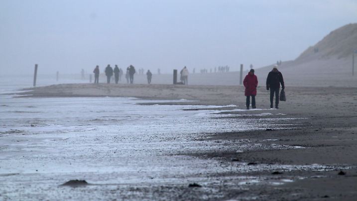 01.01.2021, Niedersachsen, Norderney: Spaziergänger sind am Weststrand der Nordsee-Insel unterwegs. Das neue Jahre startete mit Temperaturen um fünf Grad grau und windig. Foto: Volker Bartels/dpa +++ dpa-Bildfunk +++