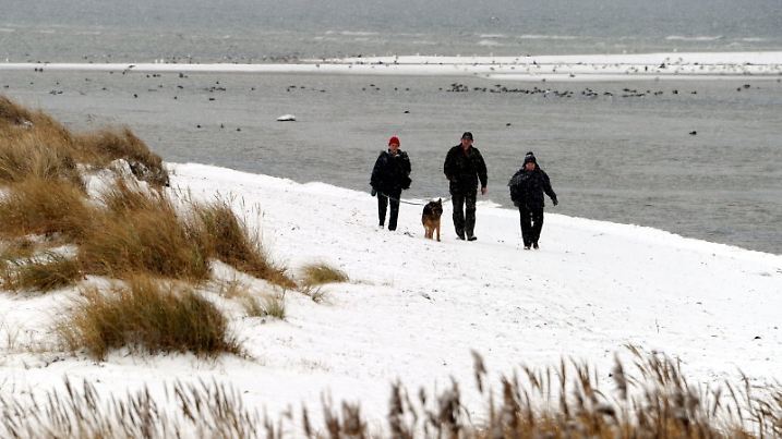 Spaziergänger laufen am 22.02.2012 in Stein bei Laboe (Schleswig-Holstein) über den schneebedeckten Ostseestrand. Auch am Wochenende wird das Wetter im Norden winterlich bleiben. Foto: Carsten Rehder/dpa +++(c) dpa - Bildfunk+++