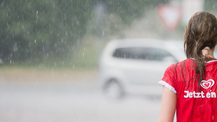 Eine Frau läuft am 27.07.2013 während einem Unwetter über eine Straße in Hannover (Niedersachsen). Auf ihrem T-Shirt steht "Jetzt ein Eis!". Ein Gewitter mit Starkregen und Hagel zog am Samstagnachmittag über die Landeshauptstadt hinweg. Foto: Julian Stratenschulte/dpa +++(c) dpa - Bildfunk+++