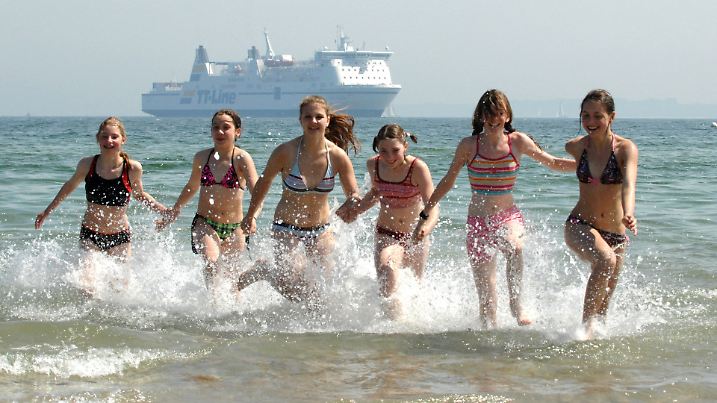 Mädchen der Akrobatikgruppe "Acroliner" laufen bei 12 Grad Wasser- und 20 Grad Lufttemperatur und strahlendem Sonnenschein aus der Ostsee vor Travemünde am Sonntag (06.06.2010). Die Gruppe trat beim RSH-Kindertag auf. Für die nächsten Tage erwarten die Meteorologen wieder kühleres und regnerisches Wetter. Foto: Wolfgang Langenstrassen dpa/lno  +++(c) dpa - Bildfunk+++