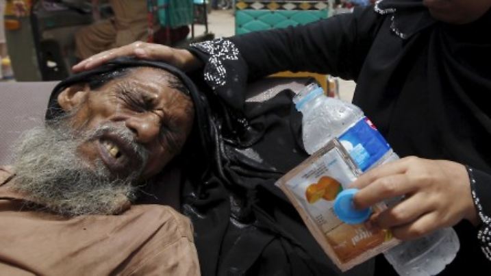 A woman (R) wets her burqa to cool her father's head outside the Jinnah Postgraduate Medical Centre (JPMC) in Karachi, Pakistan, June 24, 2015. Pakistan's financial capital of Karachi is wilting in a four-day heat wave that has killed more than 780 people, a health charity said on Wednesday, as the government declared a holiday in the city to encourage people to stay home and cool off. REUTERS/Akhtar Soomro