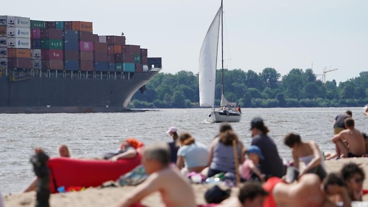 Passanten genießen das Sonnenwetter am Elbstrand in Ovelgönne.