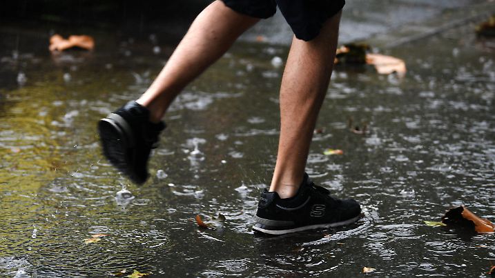 05.07.2018, Nordrhein-Westfalen, Dortmund: Ein Mann läuft bei Regen durch eine Pfütze. Foto: Ina Fassbender/dpa +++ dpa-Bildfunk +++