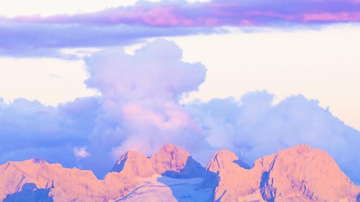 Sonnenuntergang in der Dachsteingruppe: Blick aus der Osterhorngruppe bei Sonnenuntergang über den Einberg zum Dachsteinmassiv mit Torstein, Gosaugletscher, Hoher Dachstein, Niederer Dachstein, Hohes Kreuz und Niederes Kreuz. Über den Bergen lösen sich die Wolken einer sich auflösenden Störung gegen Abend hin auf |