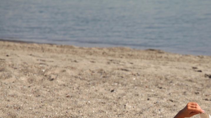 Eine Frau im Bikini liegt am Strand der Ostsee in Timmendorfer Strand und liest ein Buch im Juli 2012.  Foto: Wolfram Steinberg | Verwendung weltweit