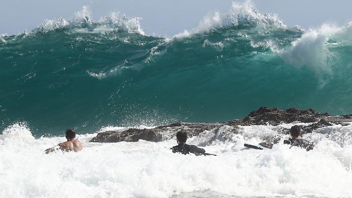 12.02.2023, Australien, Snapper Rocks: Surfer schwimmen vor den Snapper Rocks an der Gold Coast. Die Norfolkinsel bereitet sich auf den Zyklon Gabrielle vor, der beim Erreichen des abgelegenen australischen Territoriums stürmische Winde und sehr starke Brandung mit sich bringt. Foto: Jason O'brien/AAP/dpa +++ dpa-Bildfunk +++
