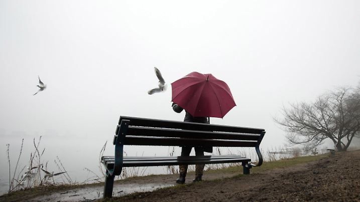 12.03.2018, Hamburg: Bei Nebel und leichtem Nieselregen füttert eine Frau Möwen an der Außenalster. Foto: Christian Charisius/dpa +++ dpa-Bildfunk +++