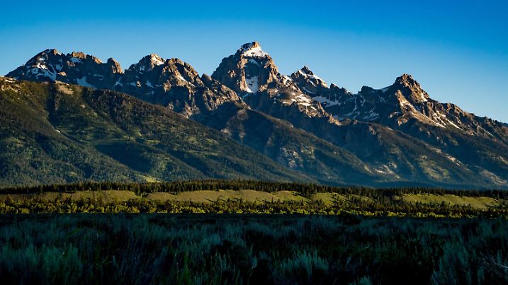 The Teton Range, a mountain range of the Rocky Mountains, is seen as the sun rises in Moose, Wyoming, United States at the Teton Point Turnout on July 13, 2018. It is south of Yellowstone National Park and most of the east side of the range is within Grand Teton National Park. (Photo by Patrick Gorski/NurPhoto) | Keine Weitergabe an Wiederverkäufer.