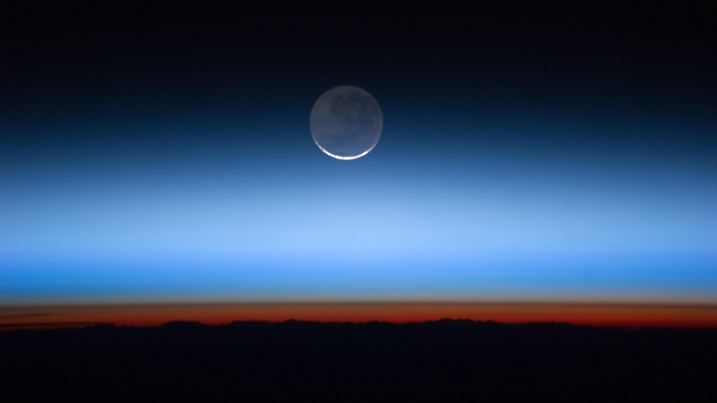 Sep. 23, 2011 - ISS, Lower Earth Orbit - Photographed by the Expedition 28 crew aboard the International Space Station, this image shows the moon, the Earth's only natural satellite, at center with the limb of Earth near the bottom transitioning into the orange-colored troposphere, the lowest and most dense portion of the Earth's atmosphere. The troposphere ends abruptly at the tropopause, which appears in the image as the sharp boundary between the orange- and blue-colored atmosphere. The silvery-blue noctilucent clouds extend far above the Earth's troposphere |