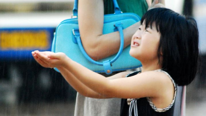 Kleine Chinesin fängt Regentropfen auf |