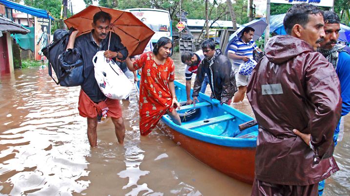 16.08.2018, Indien, Kozhikode: Flutopfer werden von Helfern evakuiert. Sintflutartige Monsunregen haben die Luft- und Zugverbindungen im südindischen Bundesstaat Kerala unterbrochen, wo, nach offizillen Angaben, Überschwemmungen, Erdrutsche und Brückeneinbrüche in der vergangenen Woche Dutzende Menschen getötet haben. Foto: K. Shijith/AP/dpa +++ dpa-Bildfunk +++