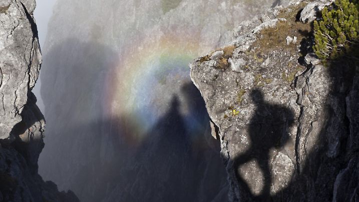 ......A mountain hiker transcending approaches the Three Sisters mountain, near Planken, Liechtenstein Friday, October 14, 2011. A rainbow like glory is seen near his shadow. A glory araound a shadow is a rare phenomenon that can be seen in the mountains. |