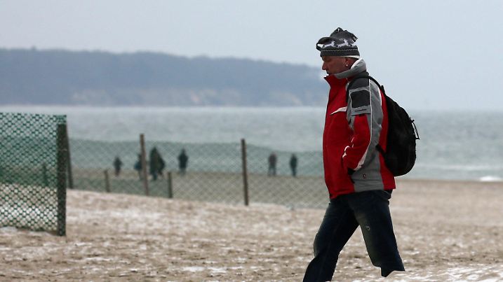 Spaziergänger gehen am 07.02.2017 über den Ostseestrand von Warnemünde (Mecklenburg-Vorpommern). Mit Schneegriesel und Frost hat sich der Winter im Norden wieder zurück gemeldet. Foto: Bernd Wüstneck/dpa-Zentralbild/dpa +++(c) dpa - Bildfunk+++