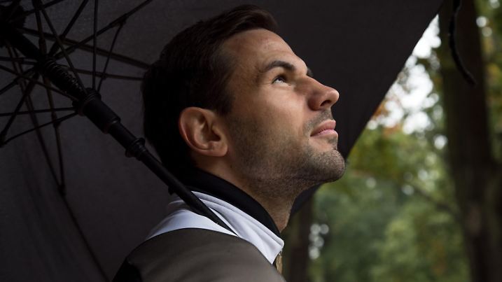 ILLUSTRATION - Ein Mann steht am 02.10.2018 in einem Park in Hamburg und haelt einen Schirm ueber seinen Kopf (gestellte Szene). Foto: Christin Klose | Verwendung weltweit