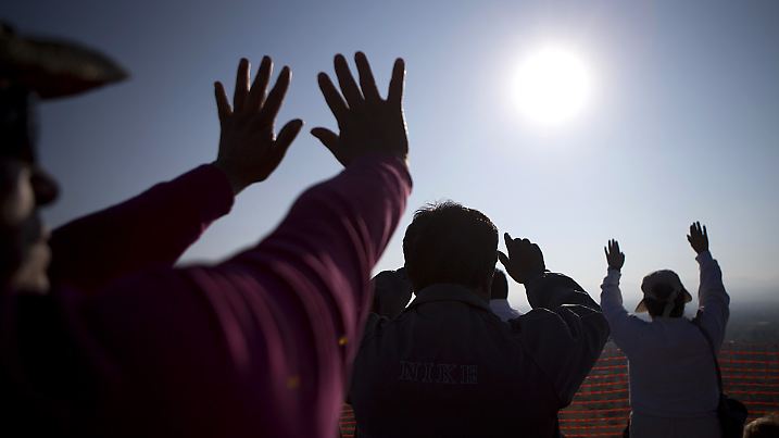 Visitors reach toward the sun as they celebrate the spring equinox atop the Pyramid of the Sun, at the Teotihuacan archeological site, in Mexico, Friday, March 21, 2014. Although the official vernal equinox occurred on Thursday, thousands of visitors were expected to climb the ancient pyramid on Friday to greet the sun and celebrate the beginning of spring. (AP Photo/Rebecca Blackwell)