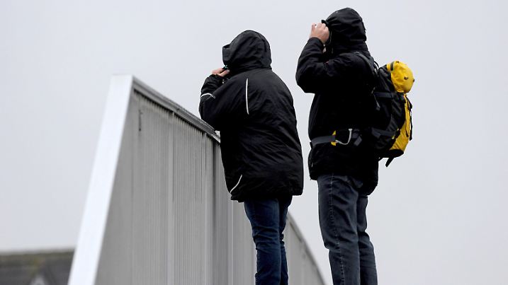 Ein Paar in Regenkleidung überquert am 08.01.2015 eine Fußgängerbrücke im Hafenbereich von Cuxhaven (Niedersachsen). Mit Regen und aufgefrischtem Wind kündigt sich ein Sturmtief für die nächsten Tage an. Foto: Ingo Wagner/dpa | Verwendung weltweit