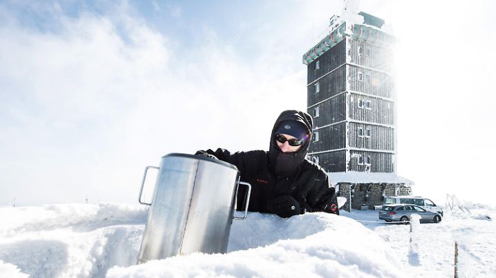 01.03.2018, Sachsen-Anhalt, Schierke: Wetterdiensttechniker Marc Kinkeldey hält einen Behälter für die Niederschlagsmessung an einer Messstation des Deutschen Wetterdienstes (DWD) auf dem Brocken im Harz. Auf dem höchsten Berg in Norddeutschland herrschen derzeit deutlich zweistellige Minusgrade. Foto: Swen Pförtner/dpa +++ dpa-Bildfunk +++